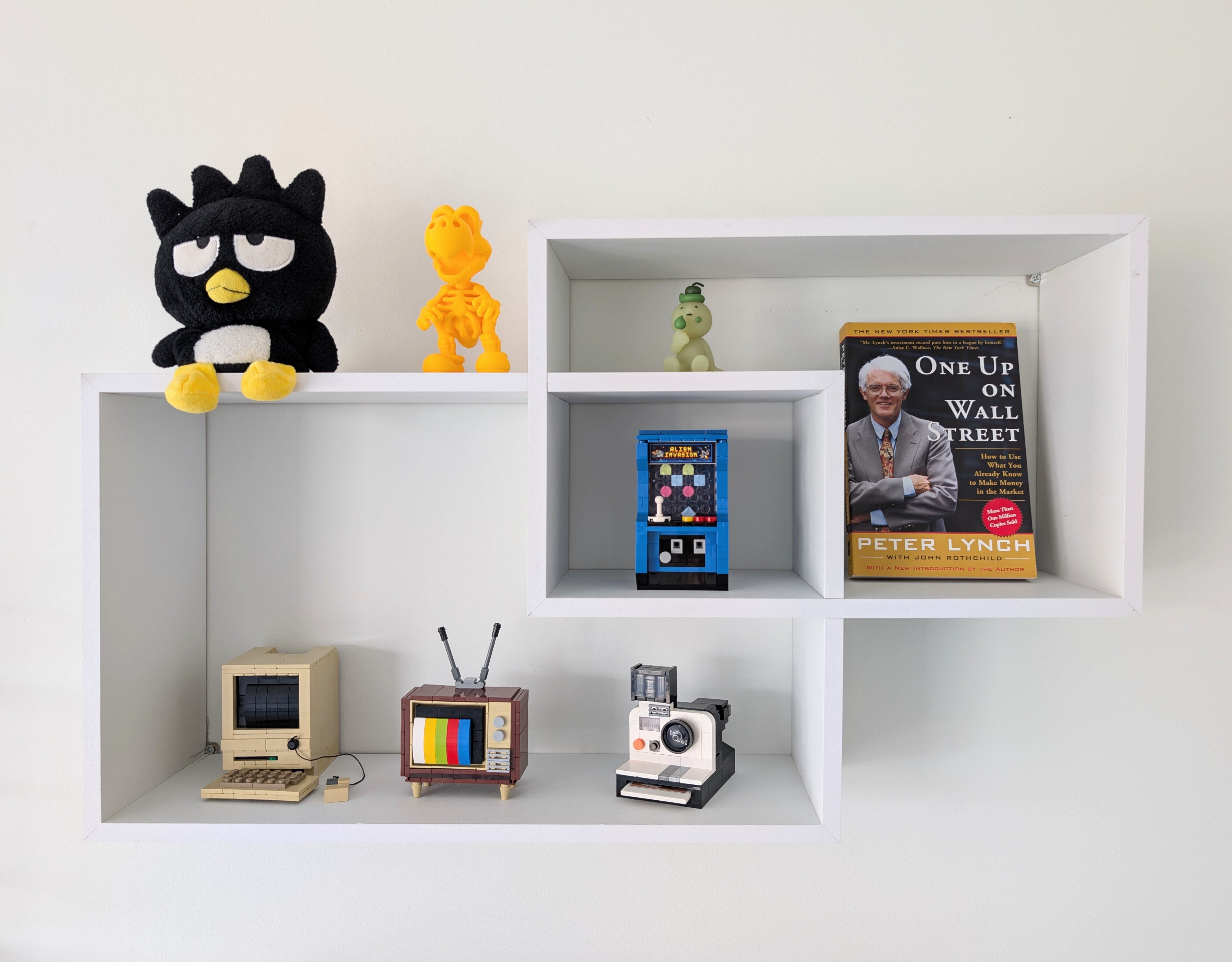 White shelving unit with various decorative items including a plush toy, figurines, books, and vintage electronic devices.