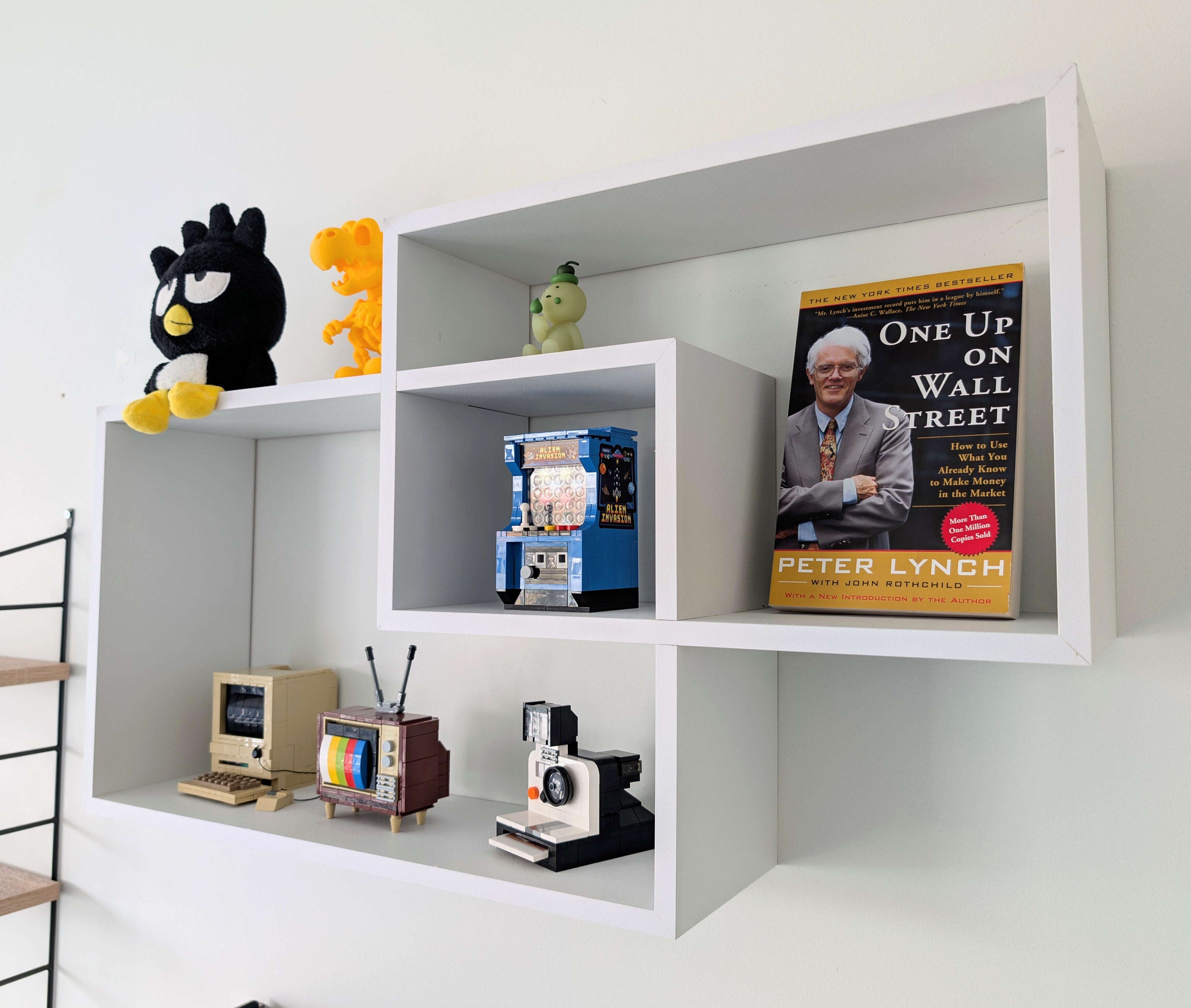 White wall shelves with decorative items including a book, toys, and vintage electronic devices.