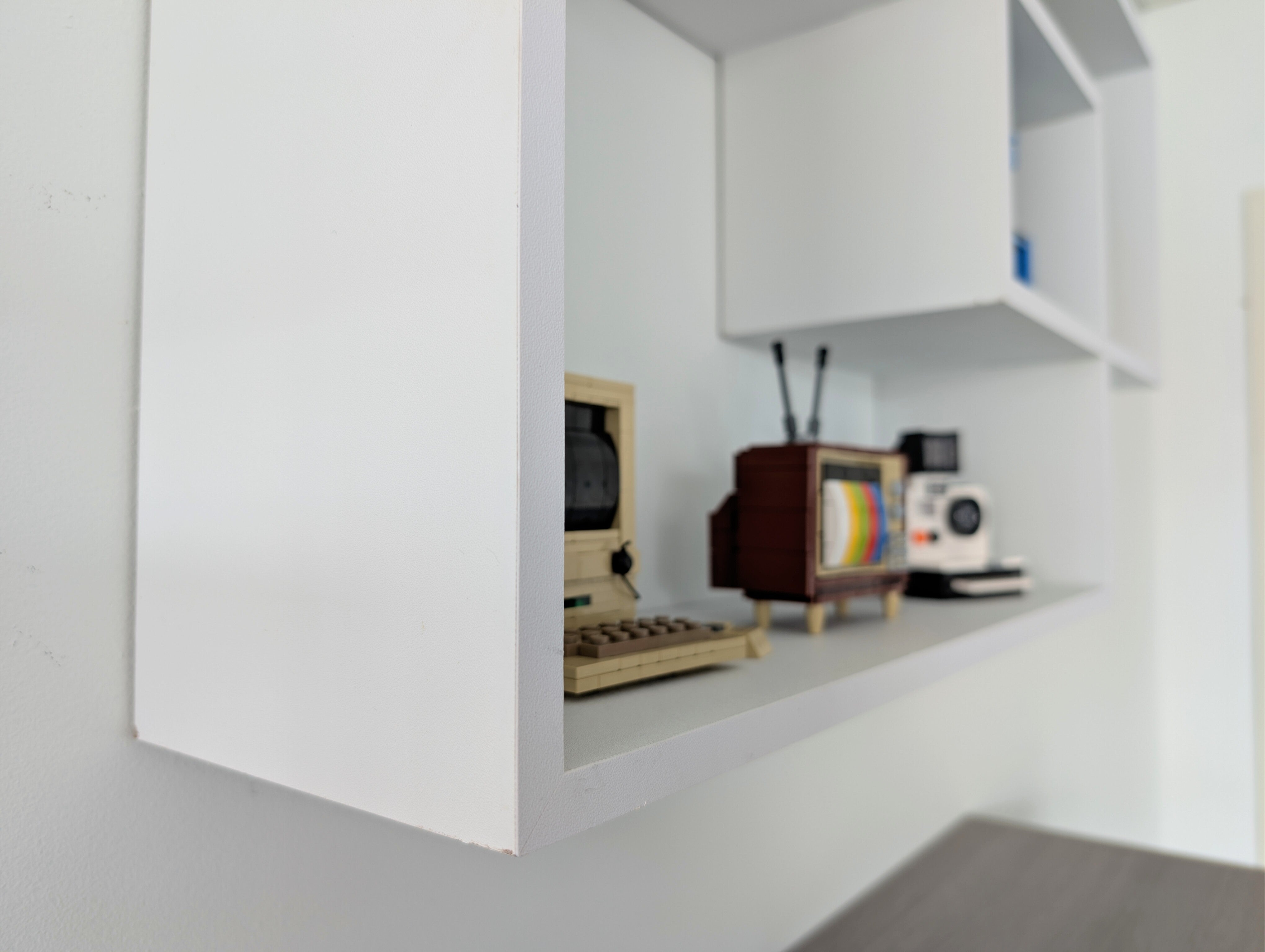 White wall-mounted shelf with vintage electronic devices on a plain background