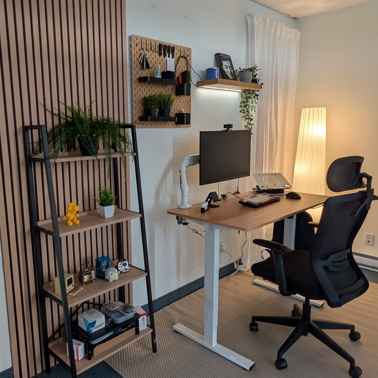 Home office setup with a standing desk, chair, computer monitor, and shelves.