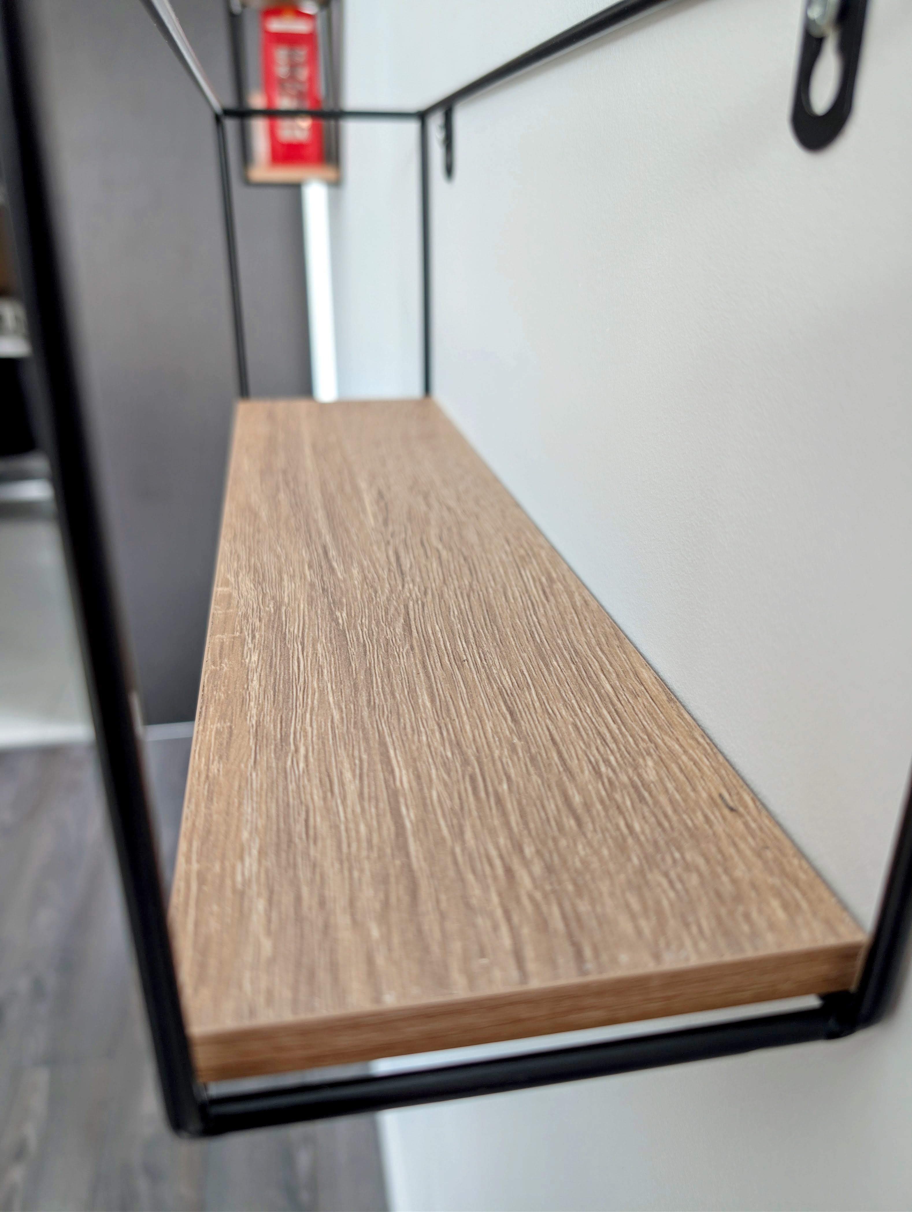 Wooden shelf mounted on a wall with black metal brackets