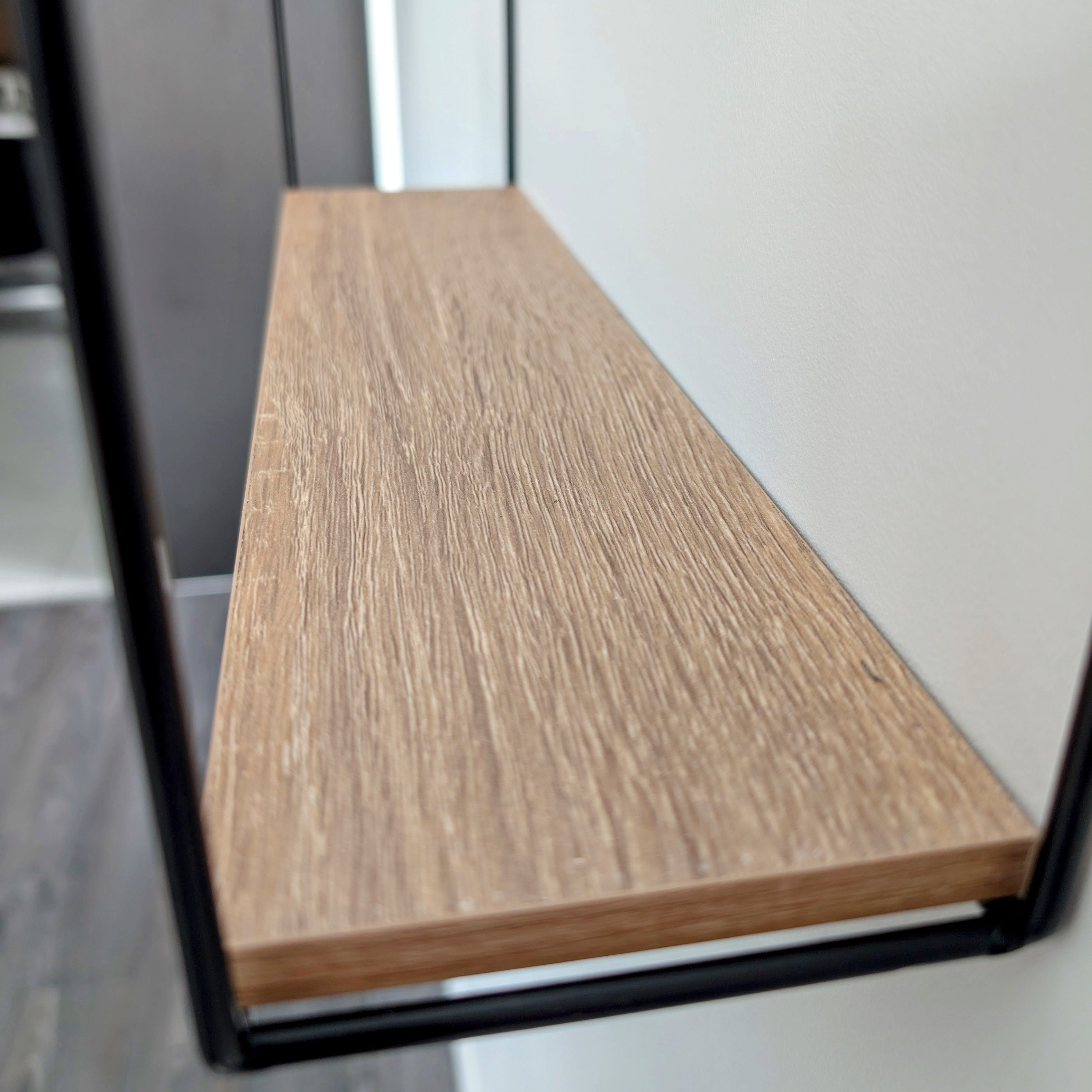 Wooden shelf mounted on a wall with black metal brackets