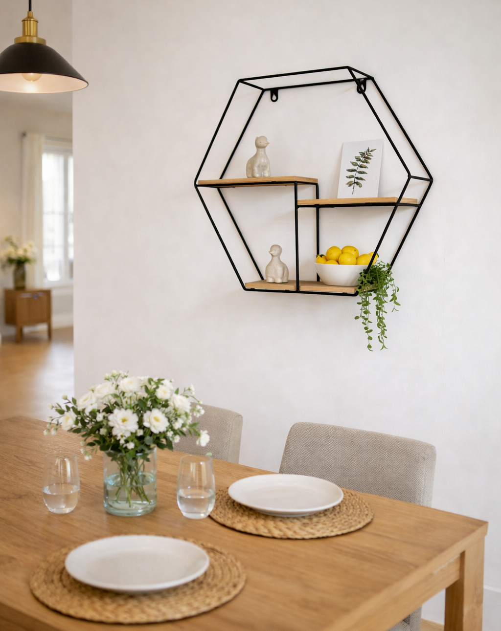 Dining room with a hexagonal wall shelf, table set with plates and glasses, and flowers.