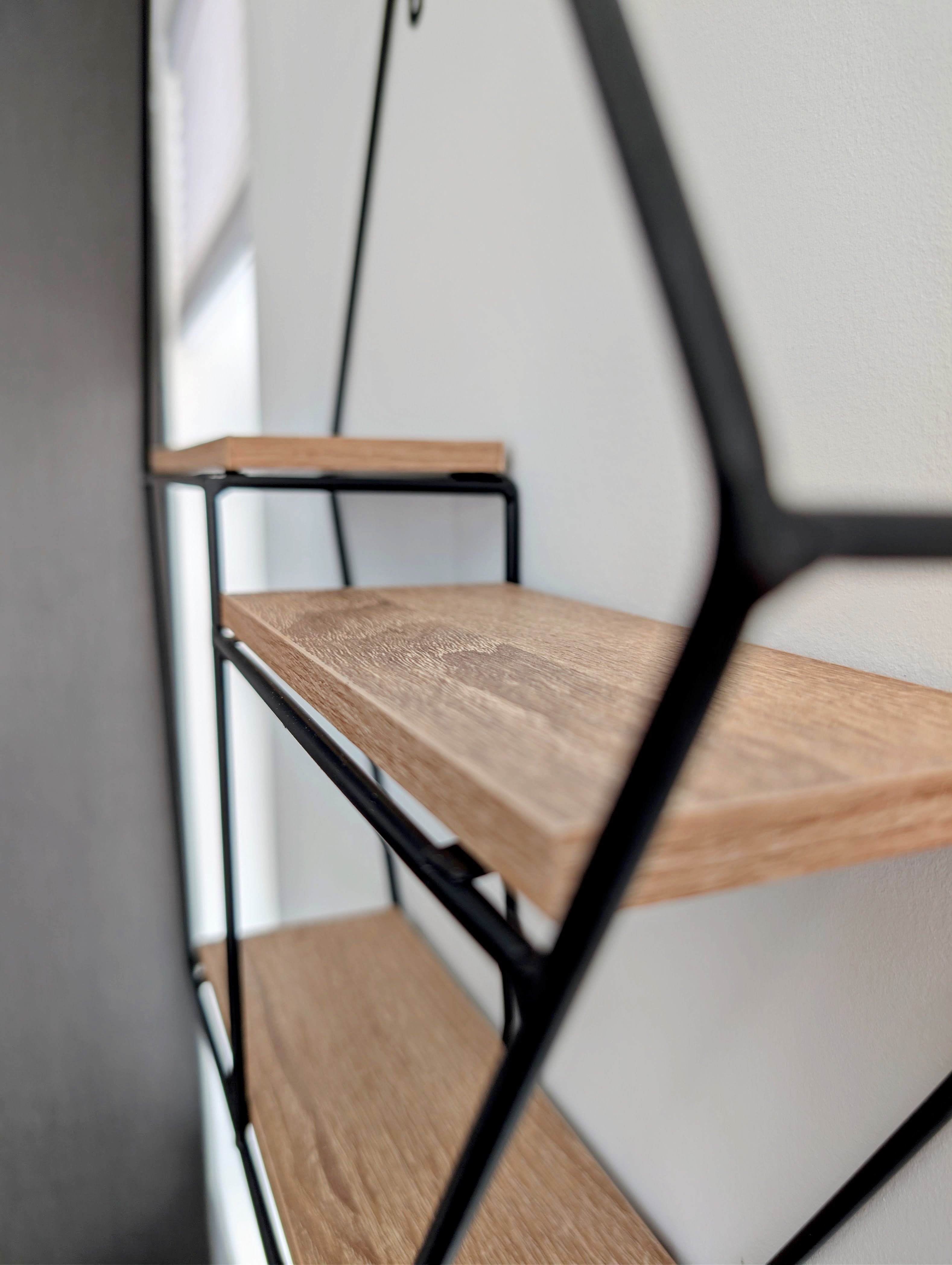 Wooden shelves with black metal frame on a white wall