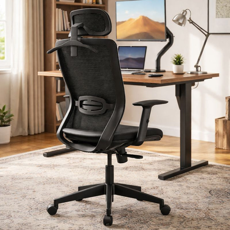 Black ergonomic chair in a home office setting with a desk and computer setup.