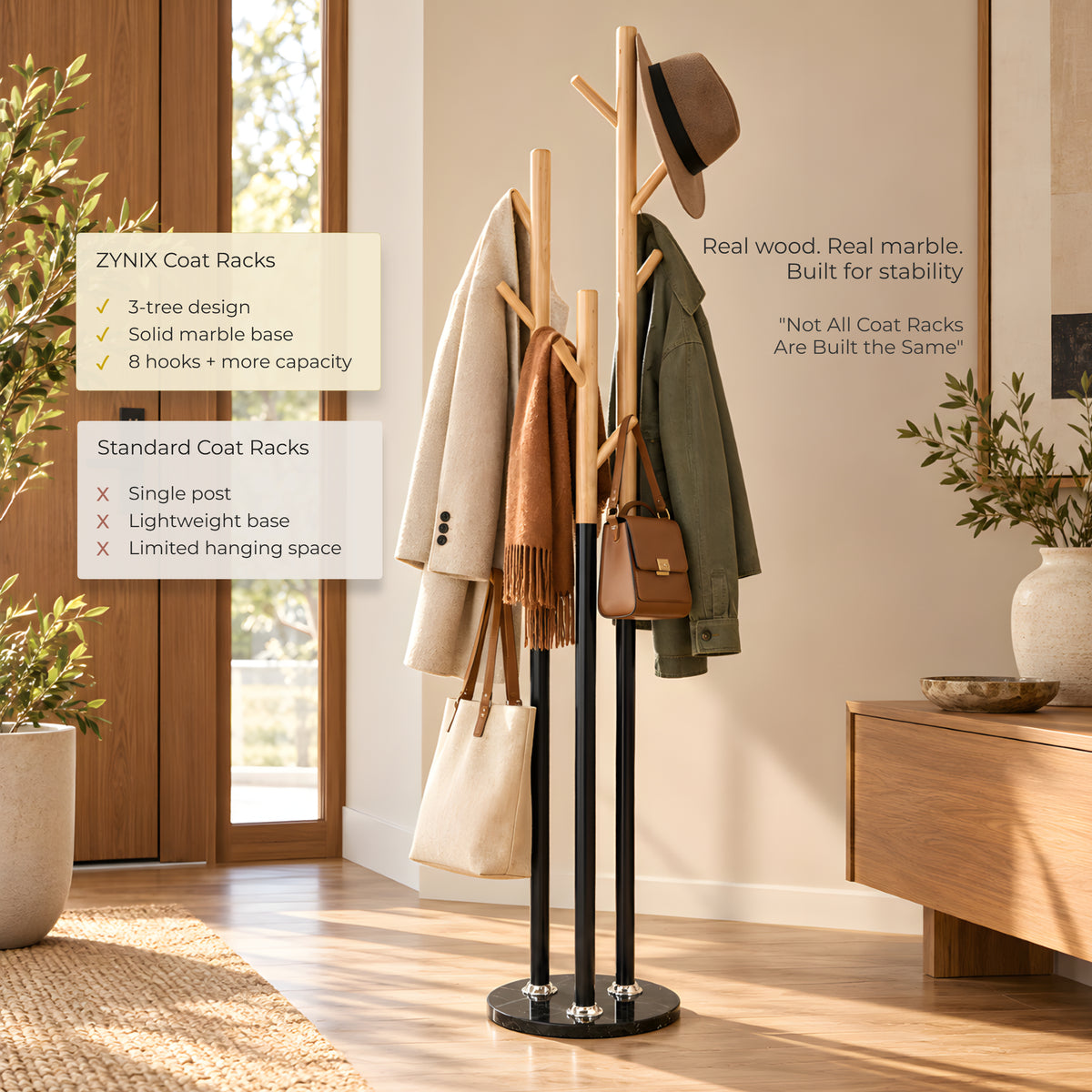 A YZNIX coat rack in a styled home entryway, featuring a 3-tree design with a solid marble base, wooden uprights, and multiple hooks holding a hat, scarf, coat, and bag. Text callouts on the left highlight product features.