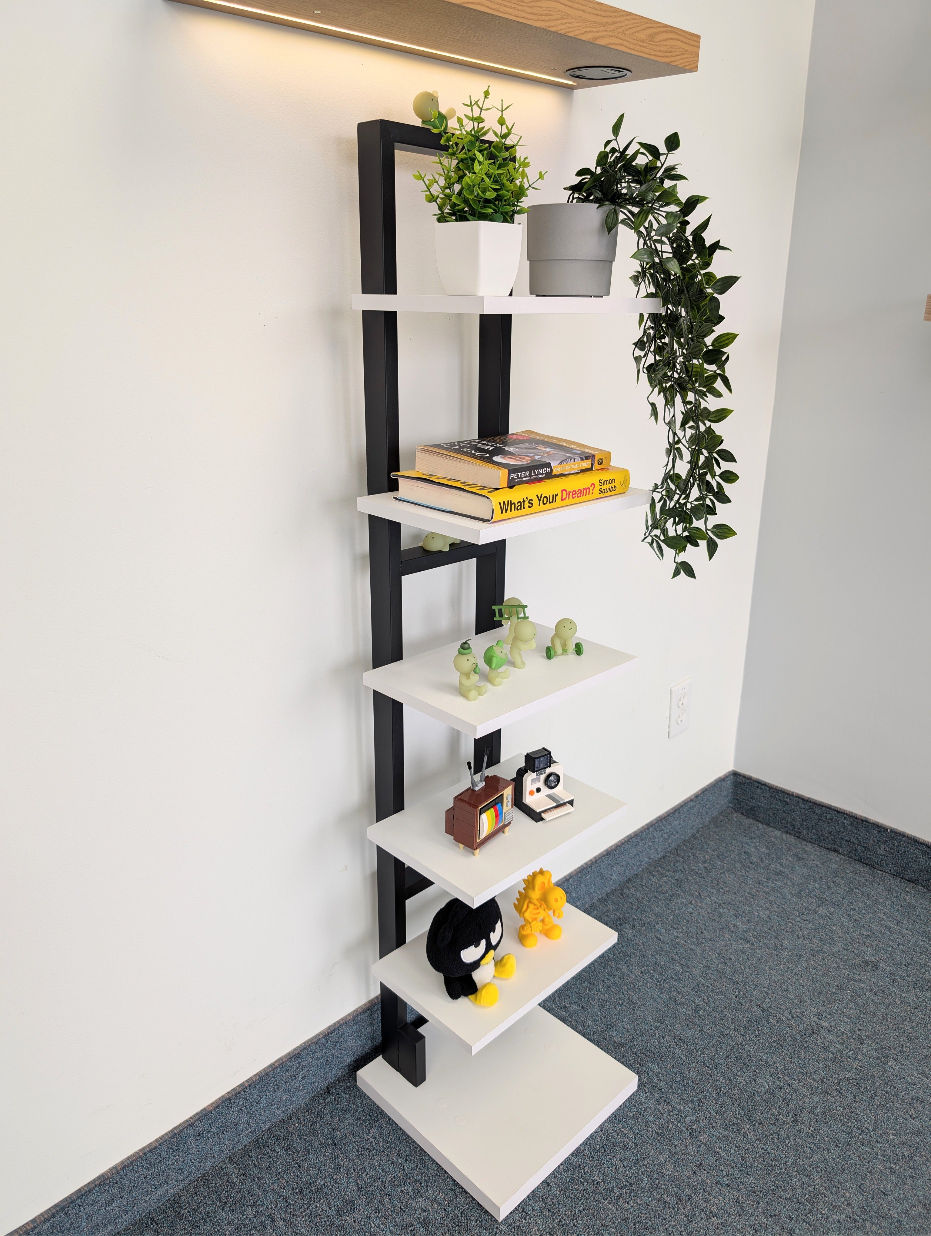 Leaning bookshelf with books and decorative items against a white wall.