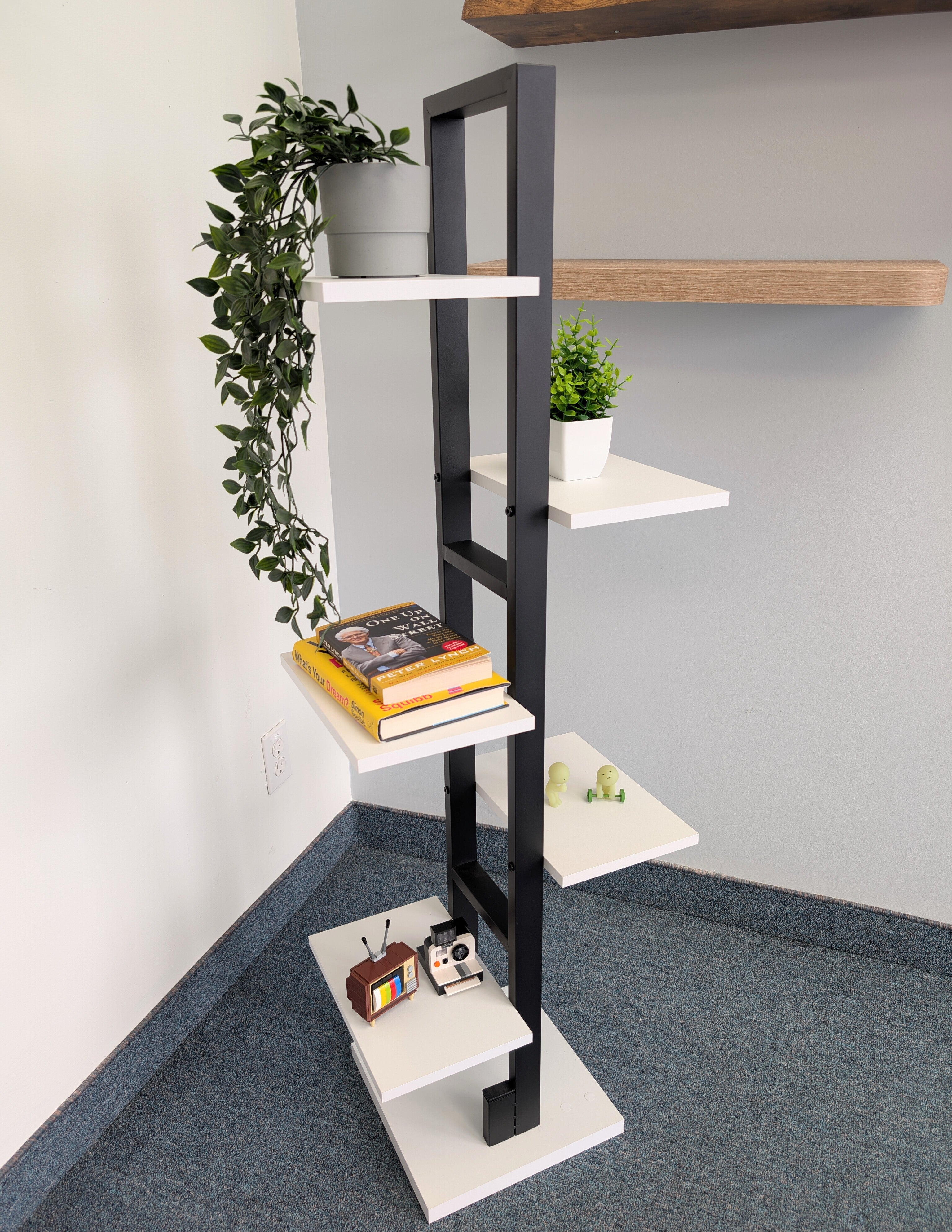 Modern corner shelf with books and plants against a gray wall.