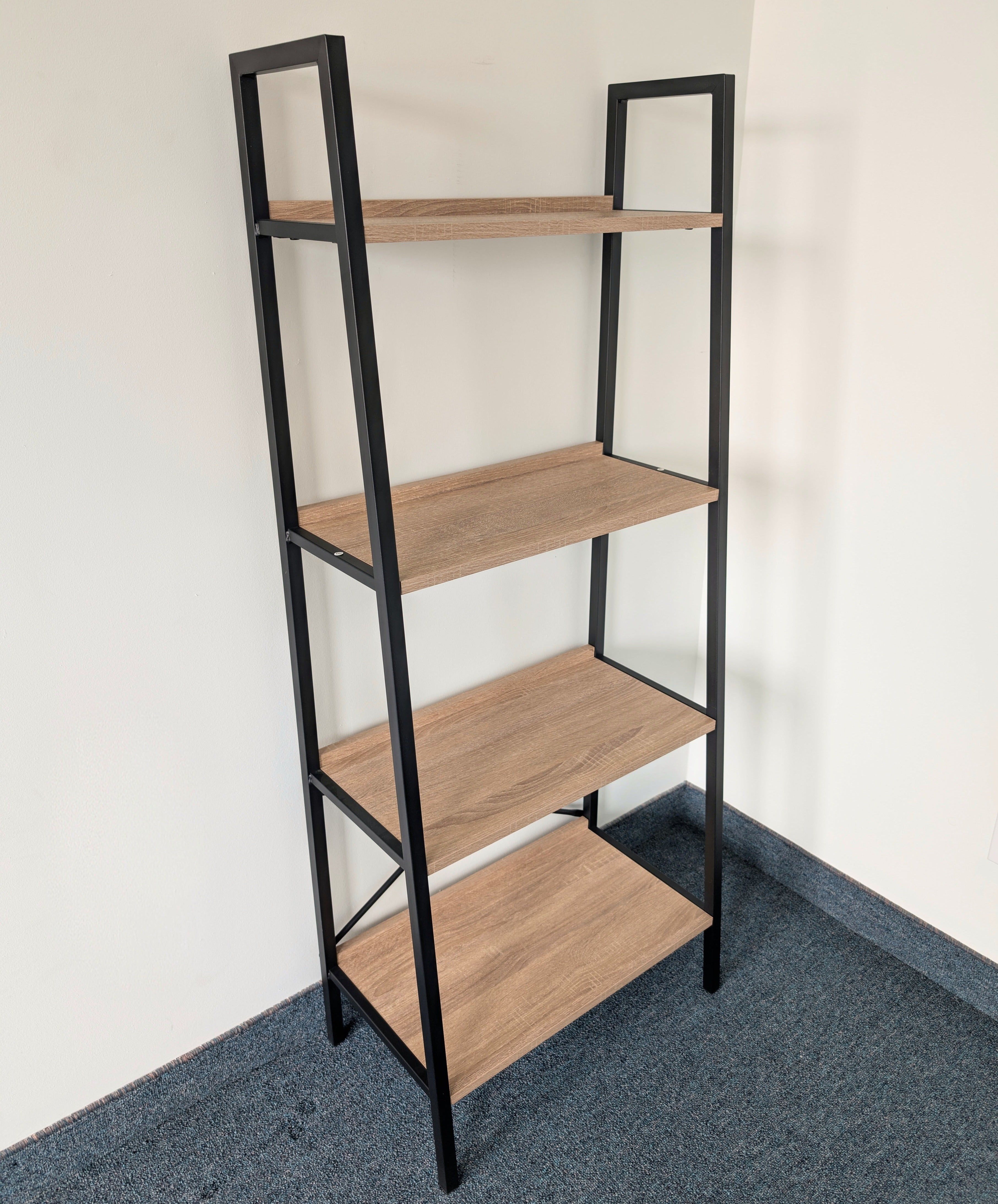 Ladder shelf with wooden shelves and black metal frame against a white wall.