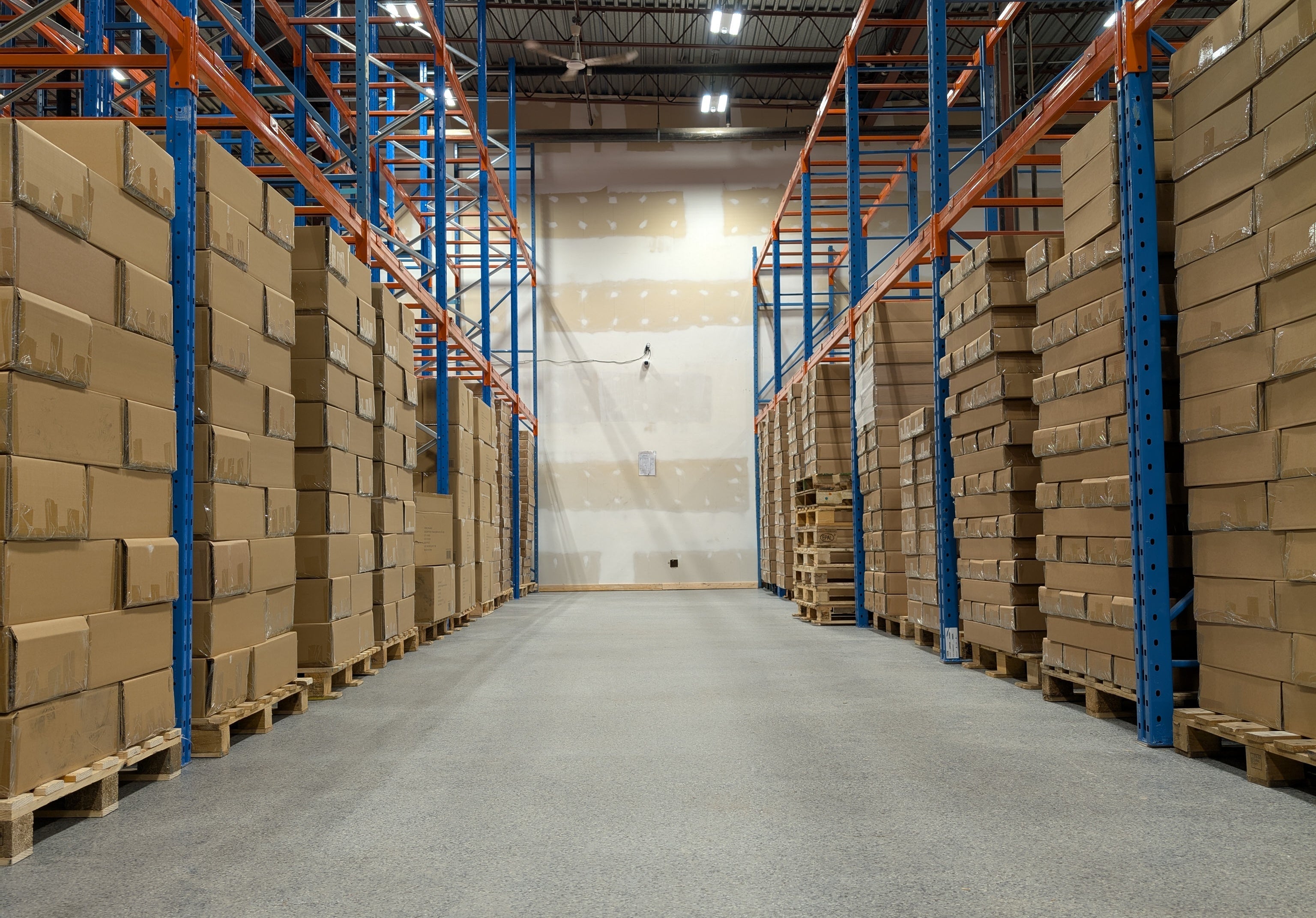 Warehouse interior with stacked cardboard boxes on pallets.