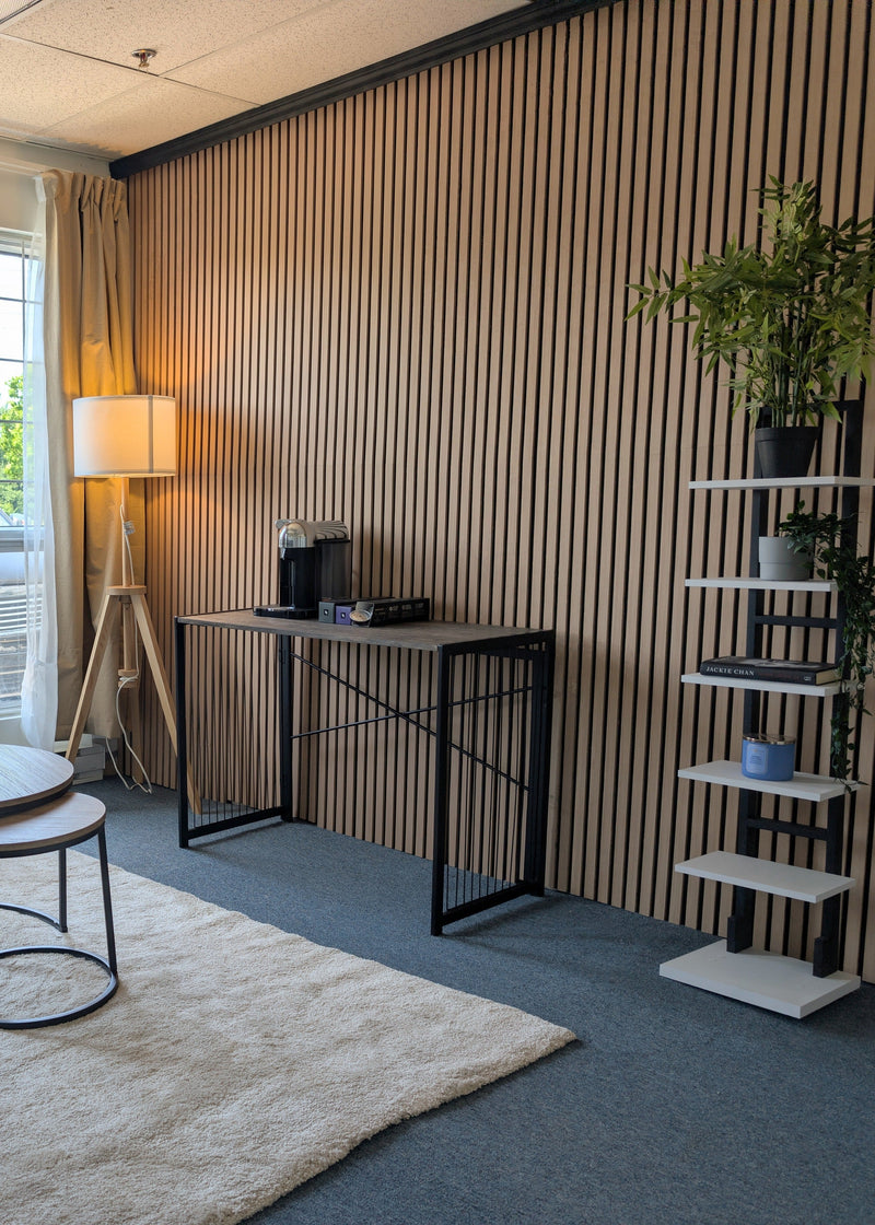 A modern living room interior with a gray sofa, round nesting tables on a white rug, a floor lamp, a slatted wood accent wall, and a white shelving unit with plants.
