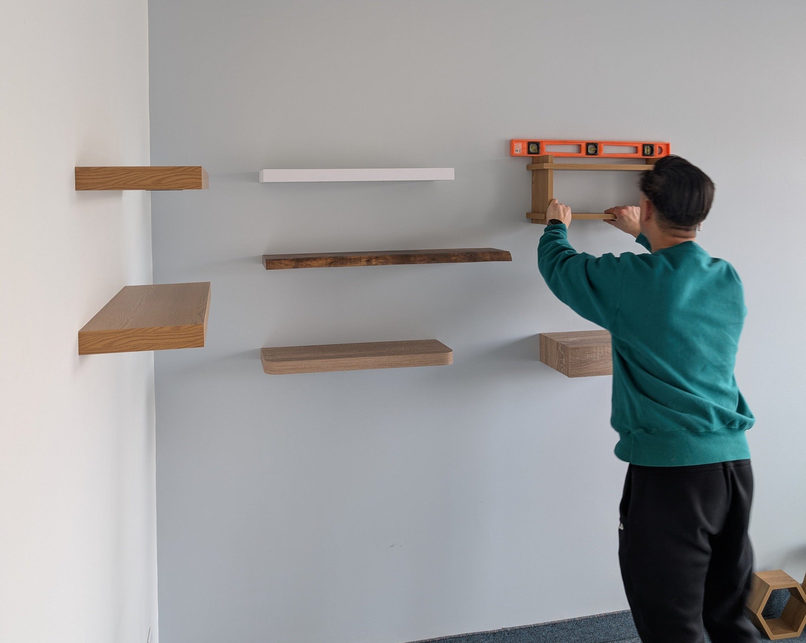 Person installing shelves on a wall using a level