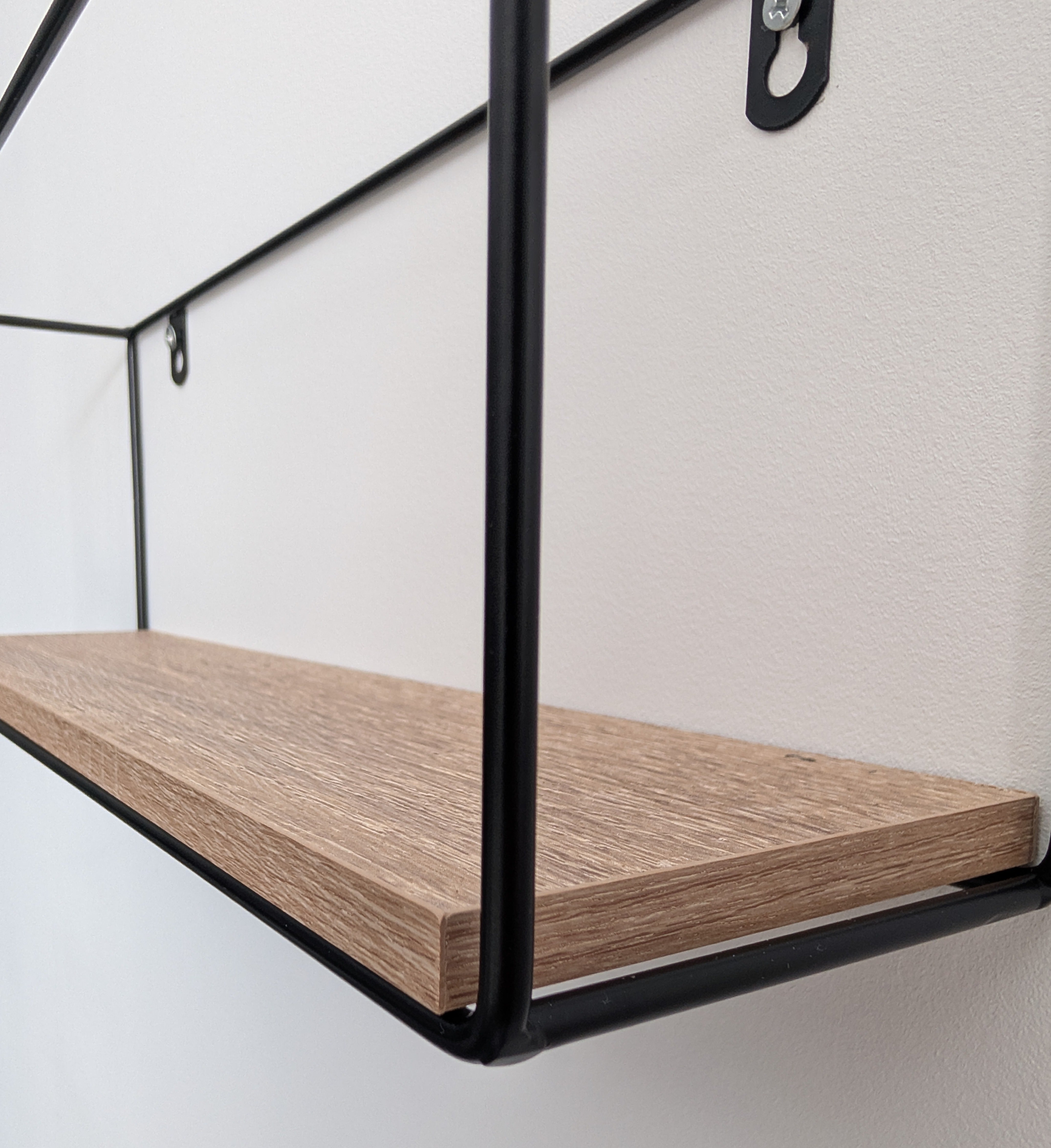 Wooden shelf with black metal brackets on a white wall