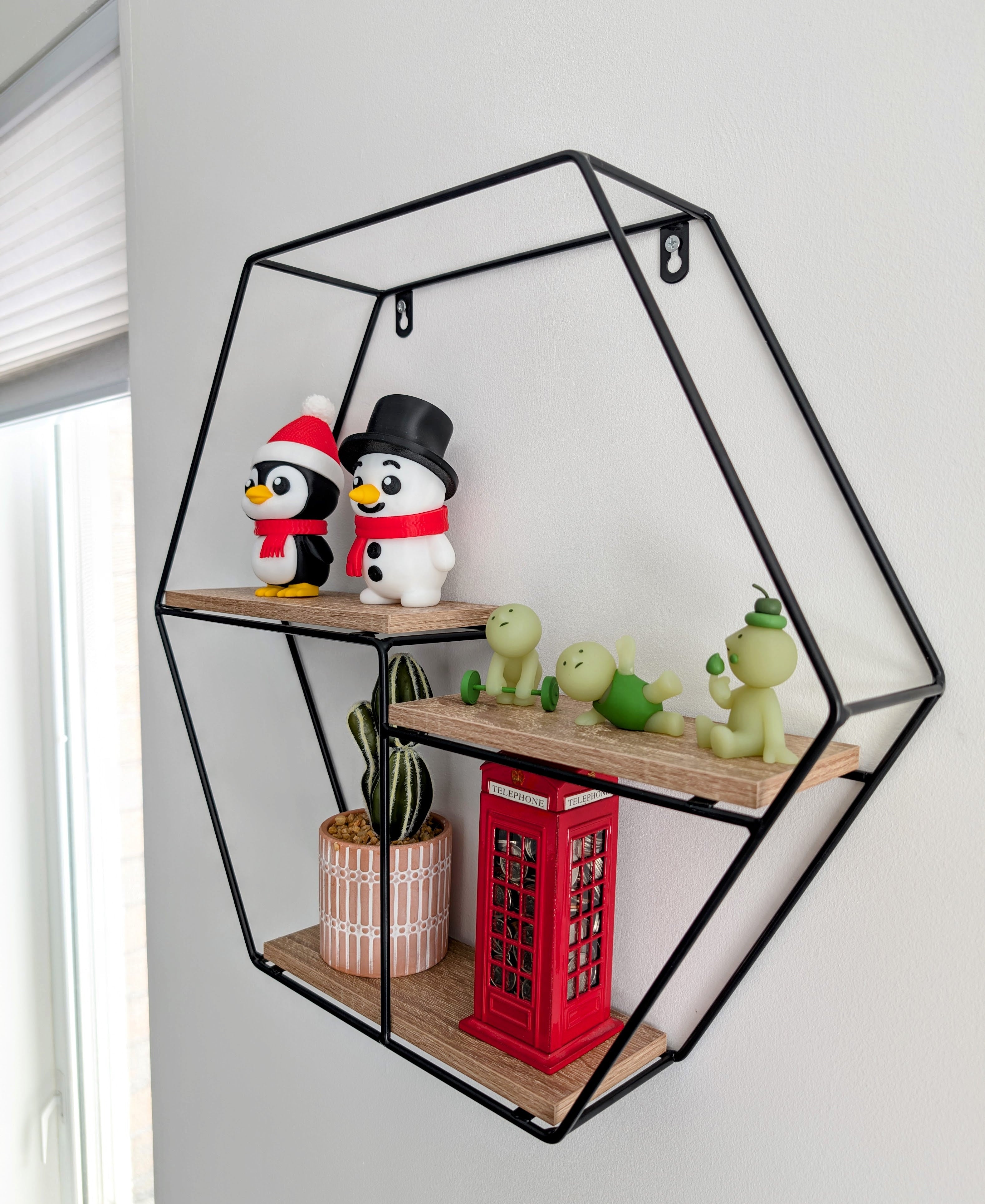 Hexagonal wall shelf with decorative items including penguins and plants on a white wall.