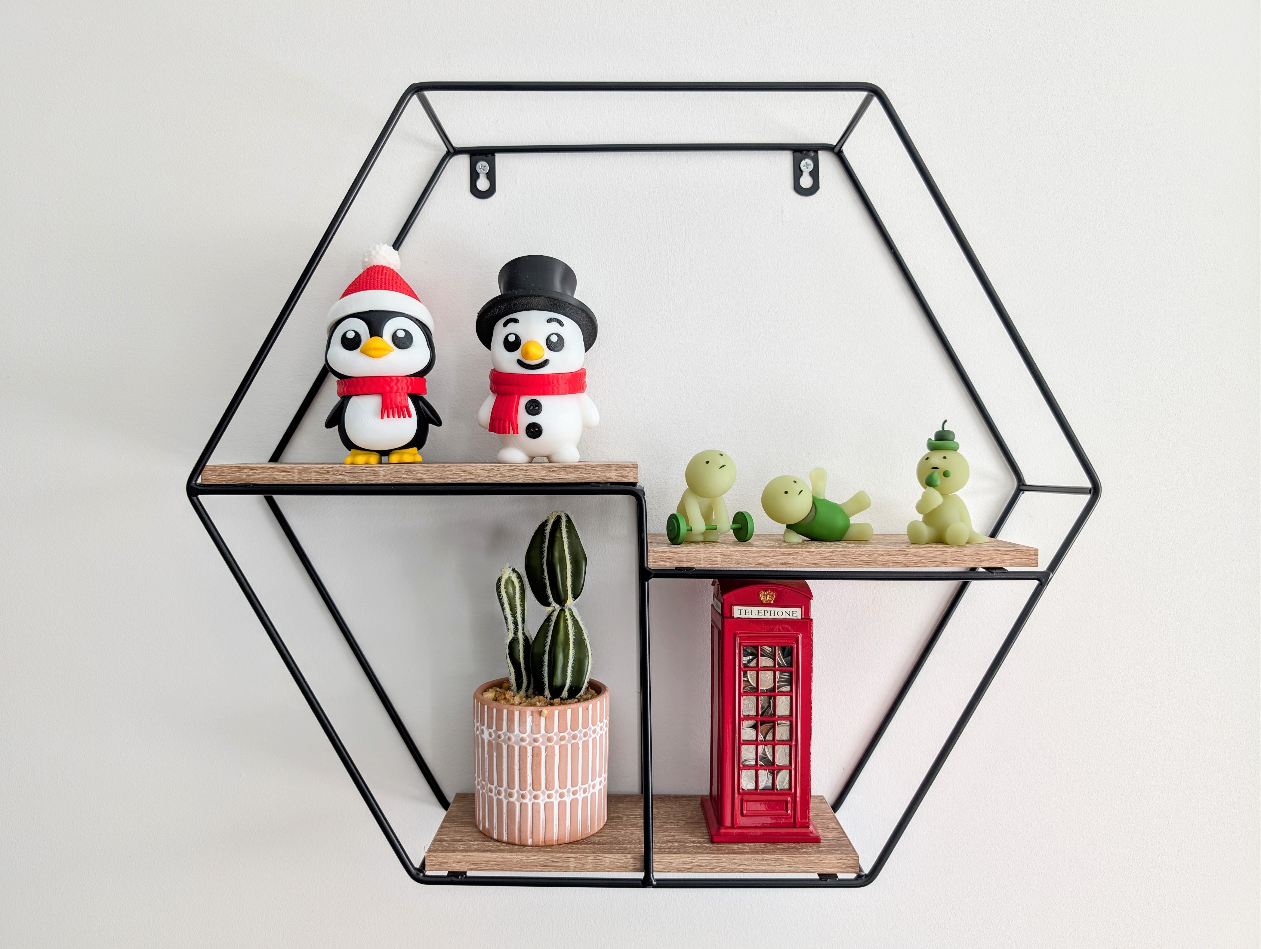 Hexagonal wall shelf with decorative items including penguins, a potted plant, and a red telephone box.